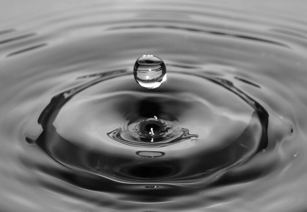 Water droplet creating ripples in liquid.